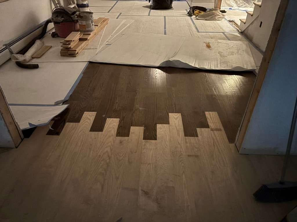 New hardwood being woven into existing floor during a home addition