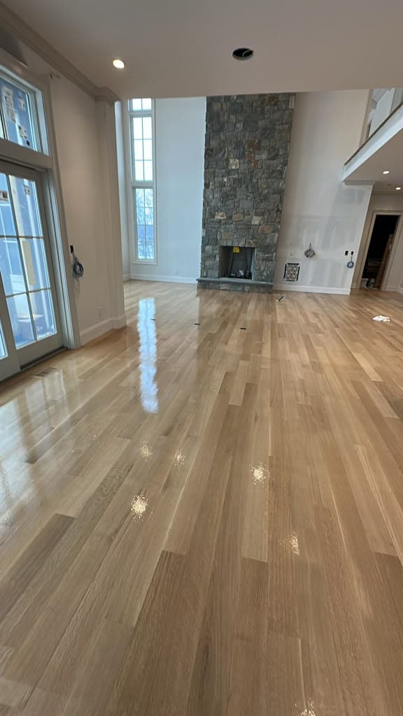 Refinished hardwood floor in great room with stone fireplace